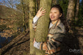 Smiling young woman hugging tree