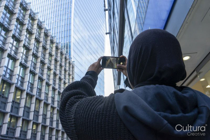 Young woman using phone to take pictures in city