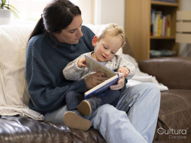 Boy sitting on mothers lap and looking at book