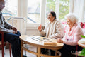 Cheerful senior people playing domino in nursing home