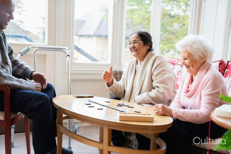 Cheerful senior people playing domino in nursing home