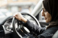 Young woman wearing hijab driving car