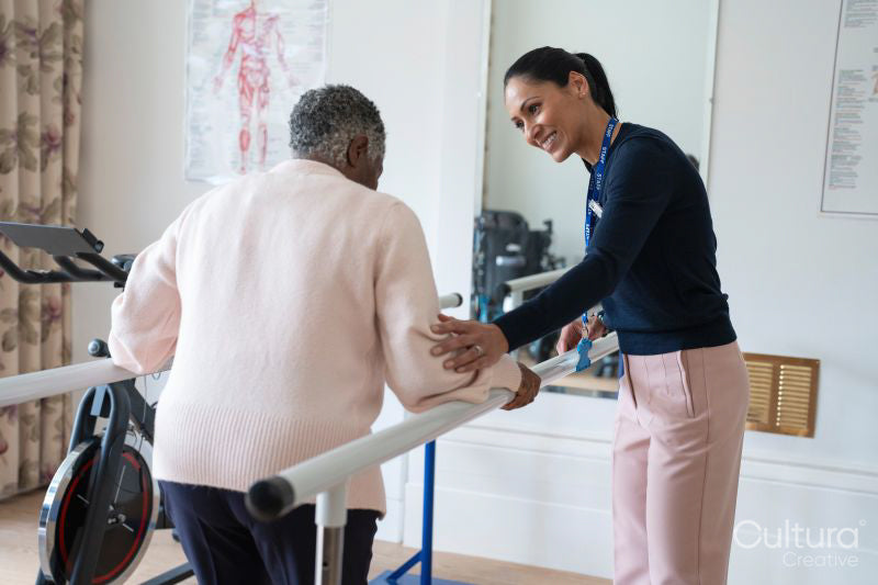 Smiling female therapist assisting senior woman walking on bars