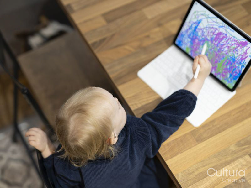 High angle of girl with hearing aid drawing on digital tablet at table
