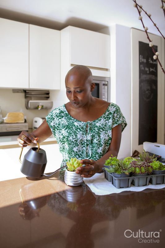 Woman watering plant in kitchen