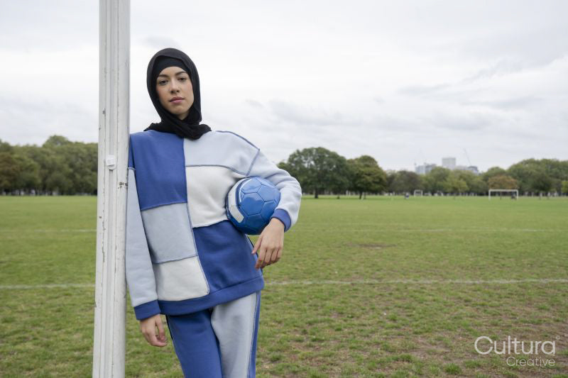 Portrait of woman in hijab standing in soccer field with soccer ball