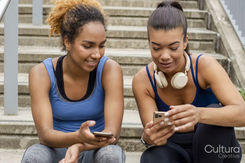 Sporty female friends using phones