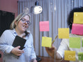 Women using adhesive notes in office