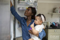 Woman looking in fridge and taking care of baby daughter