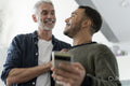 Male couple using phone at home