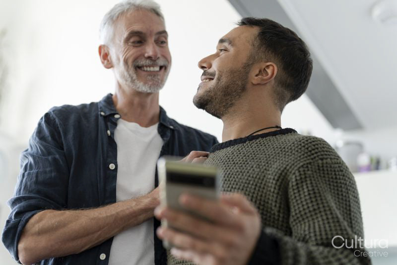 Male couple using phone at home