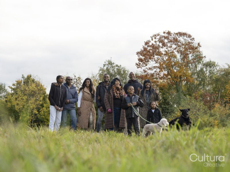 Portrait of multi-generational family walking with dog in meadow