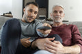 Smiling male couple watching TV at home