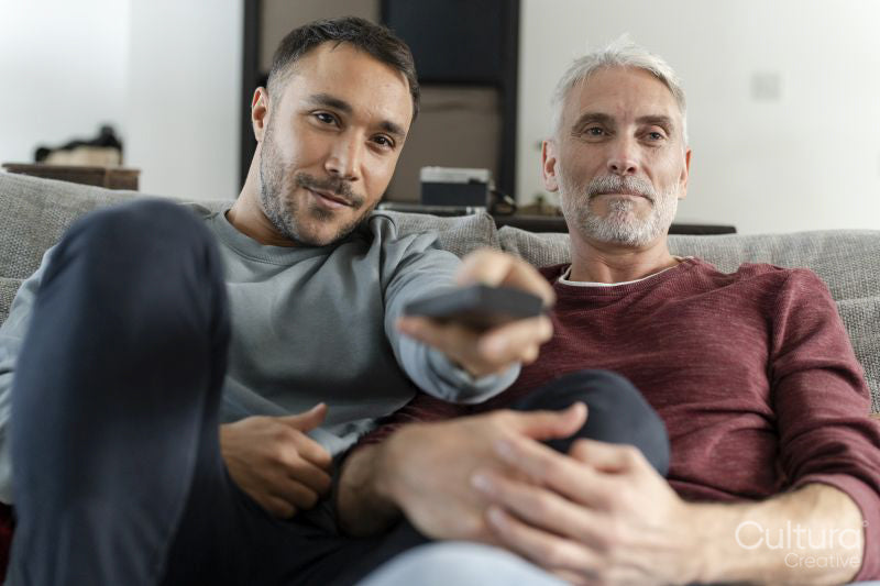 Smiling male couple watching TV at home