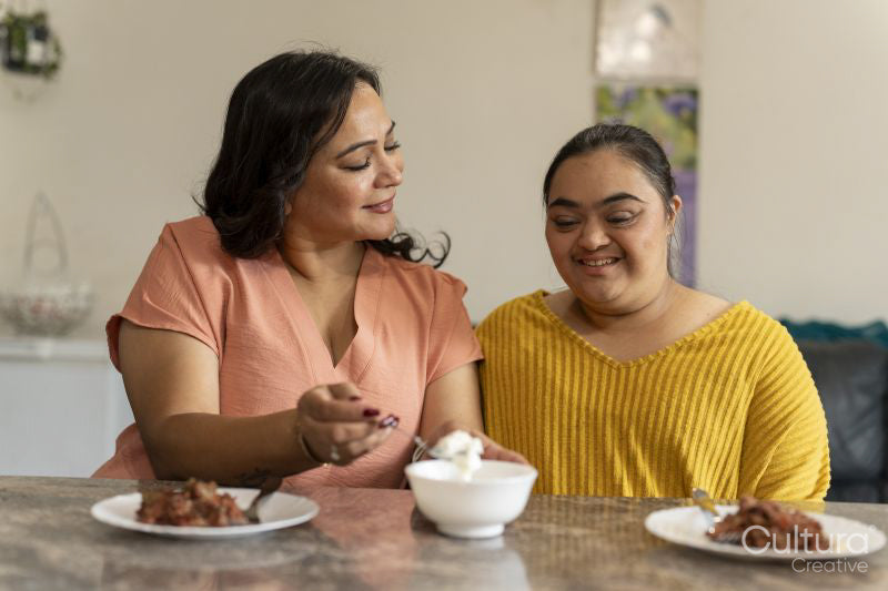 Mother eating dinner with down syndrome daughter at home