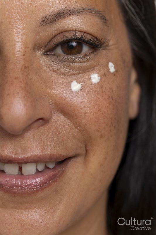 Close-up of smiling woman with dots of eye cream