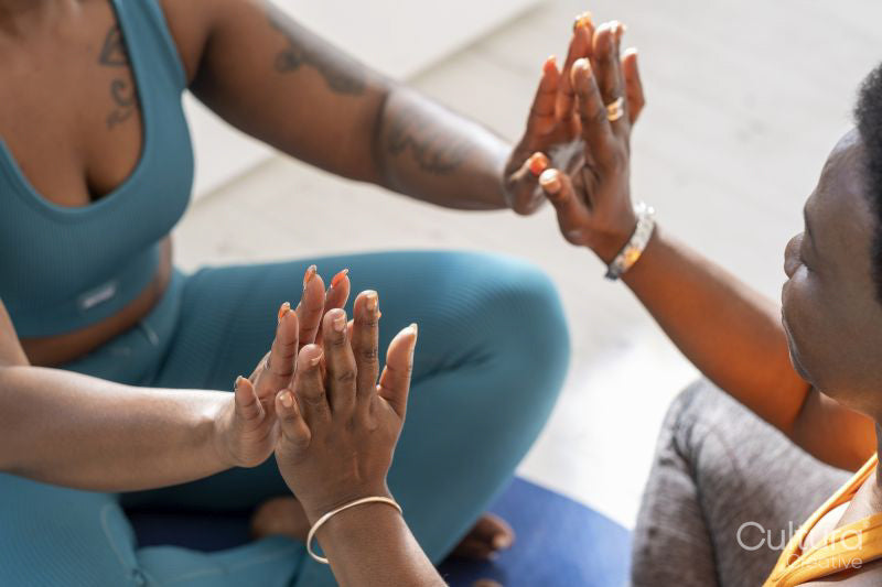 Close-up of women touching hands during yoga class