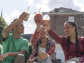 Friends toasting with smoothies on sunny day
