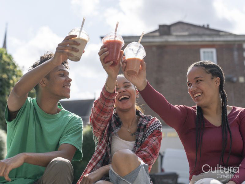 Friends toasting with smoothies on sunny day