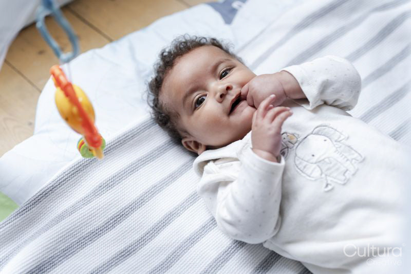 Baby girl lying on play mat at home