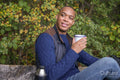 Man holding metal mug and sitting on bench