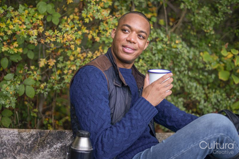 Man holding metal mug and sitting on bench