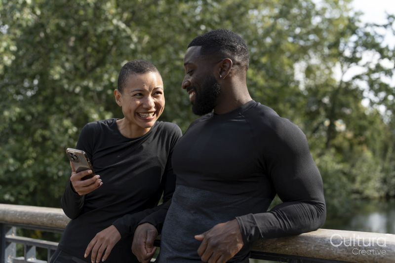 Smiling athletic man and woman holding smart phone in park