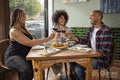 Smiling friends toasting with red wine at restaurant table