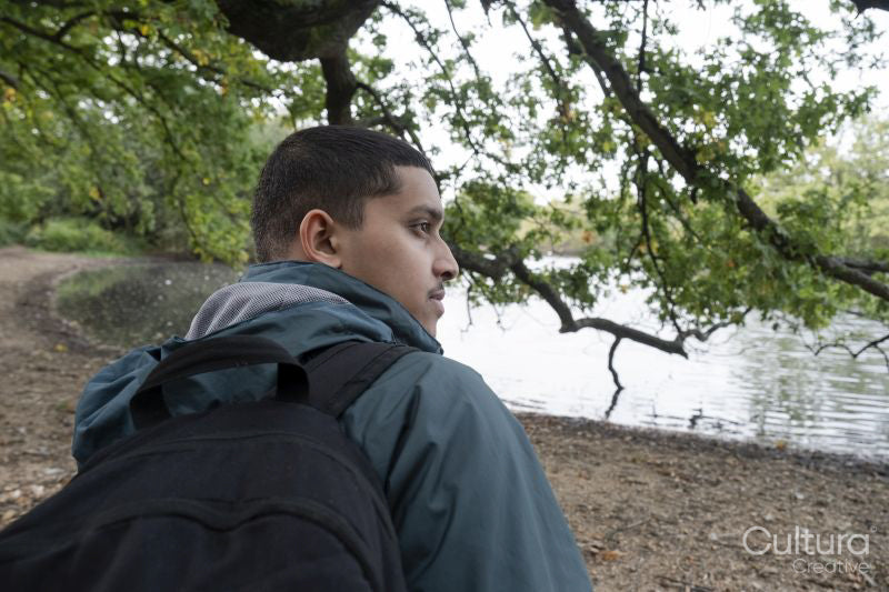 Rear view of man with backpack on riverbank
