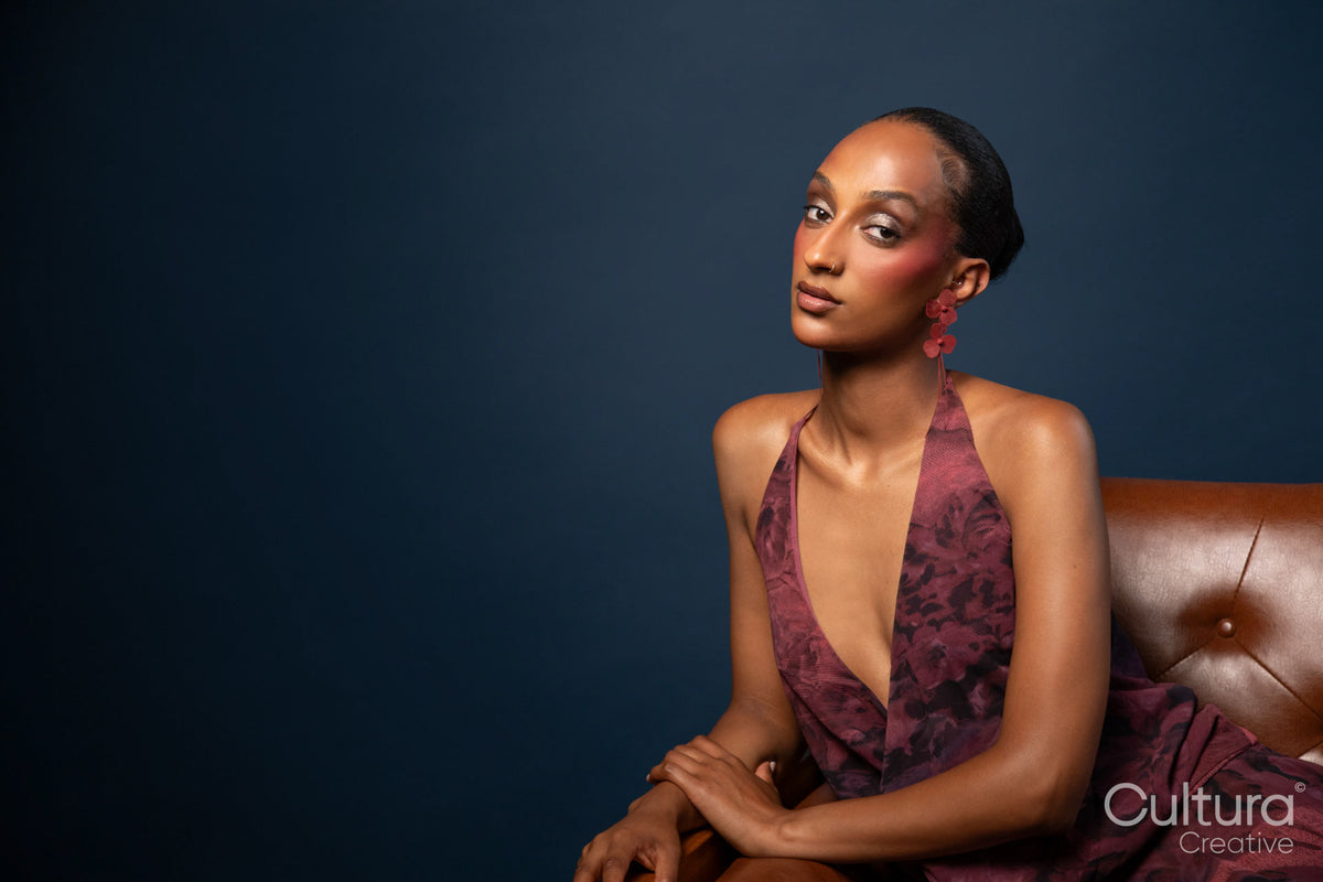 Woman in burgundy dress and red earrings on blue background
