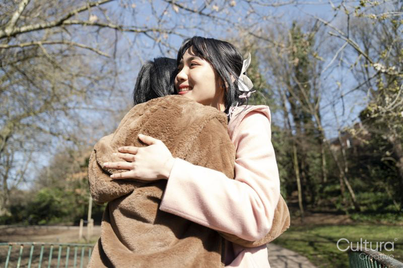 Young female friends hugging in park