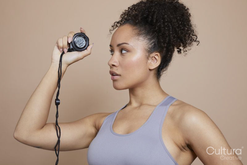 Studio portrait of athletic woman holding digital stopwatch