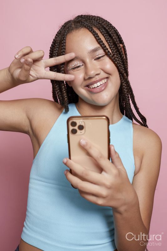 Studio shot of smiling girl with braids taking selfie