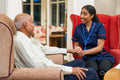 Smiling nurse looking at senior man and holding his hand
