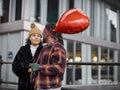 Smiling couple with red heart shaped balloon in city