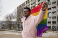 Smiling young man holding progress pride flag