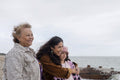 Grandmother, mother and daughter looking at sea on cloudy day