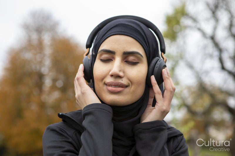 Smiling woman in hijab listening to music in park