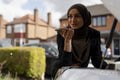 Woman wearing hijab talking on mobile phone while fixing car