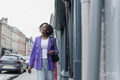Smiling woman in purple jacket walking in city