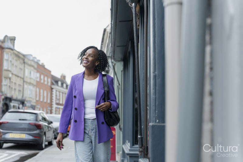 Smiling woman in purple jacket walking in city