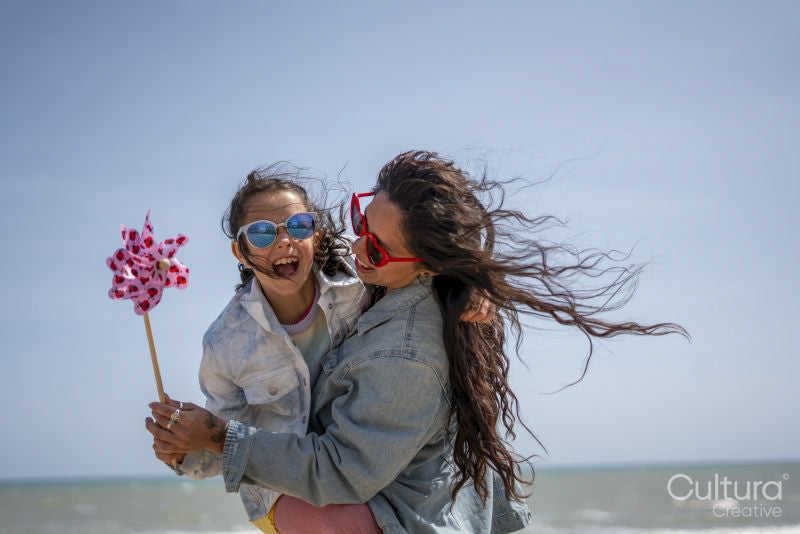 Mother and daughter playing with pinwheel on beach