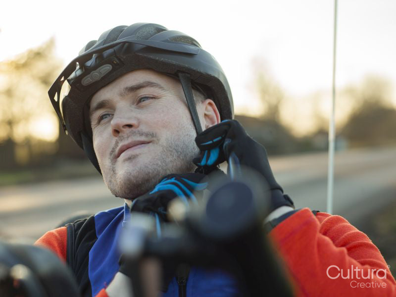 Close-up of disabled man on handcycle fastening cycling helmet on roadside