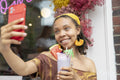 Young woman taking selfie while drinking smoothie in front of cafe
