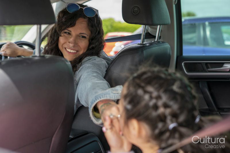 Smiling mother holding hands with daughter in car