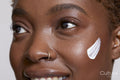 Close-up of smiling woman with face cream on cheek