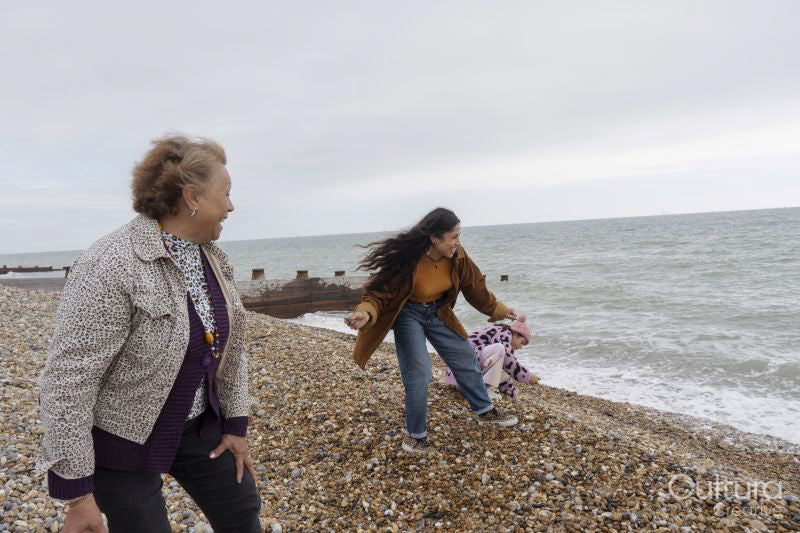 Grandmother, mother and daughter skimming stones to sea
