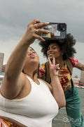 Two women taking pictures by river