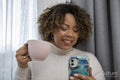 Smiling woman holding coffee cup and looking at smart phone