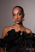 Woman in a black dress with gold earrings on a grey background